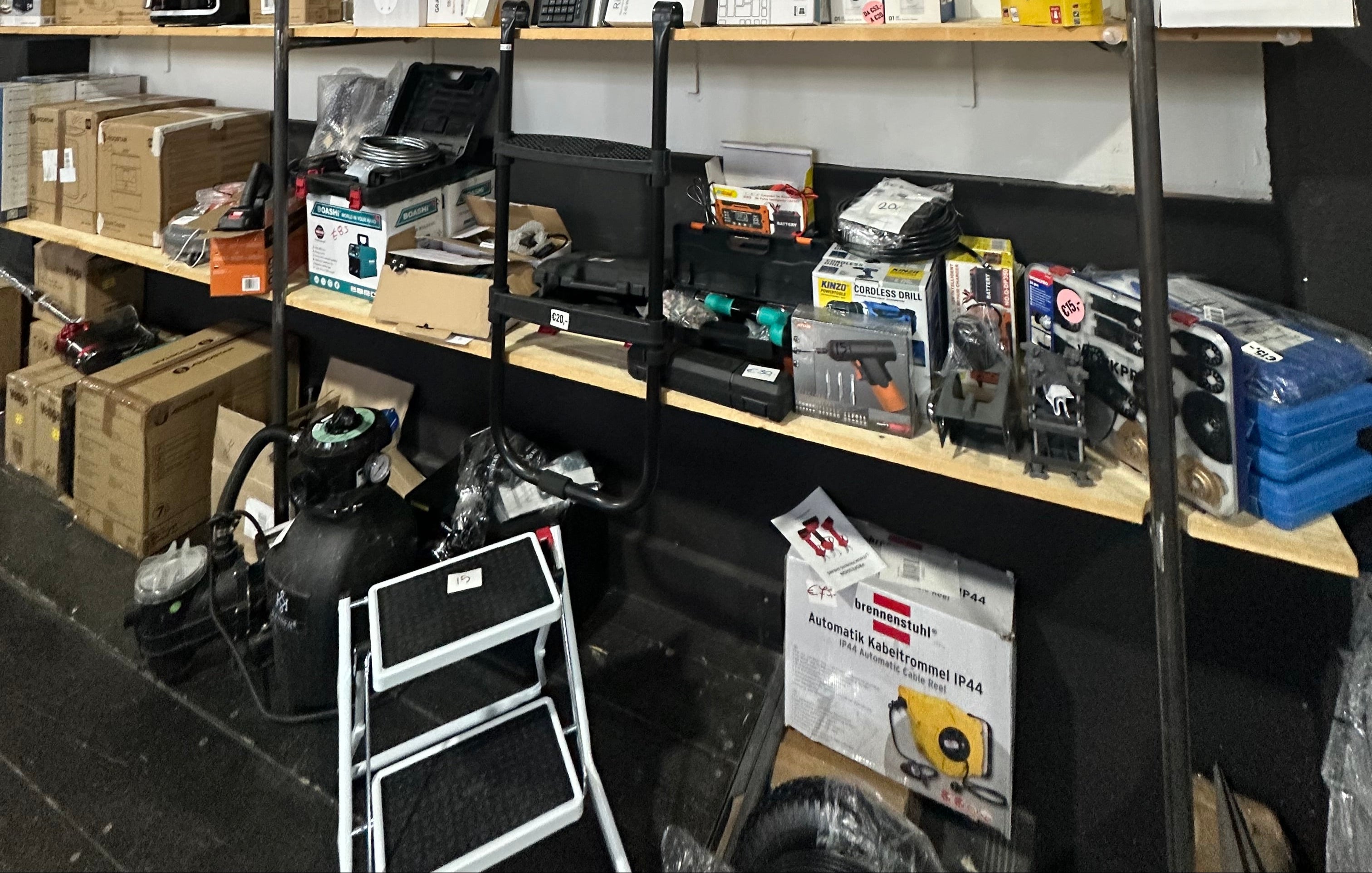 Shelves with various items including boxes and electronic equipment in a storage or warehouse setting.